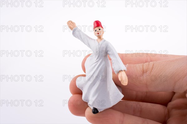 Hand holding a Sufi Dervis on a white background