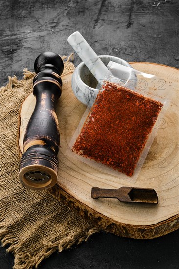 Wooden cross section with paprika in plastic package and stone mortar and mill