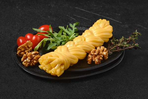 Smoked braided cheese with walnuts and tomatoes on a plate