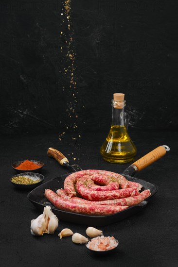 Sprinkling thin beef sausages with spice rub on grill pan