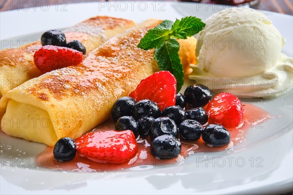 Macro photo of thin pancakes stuffed with curd and served with berry jam