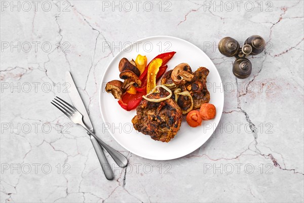 Overhead view of lamb neck with champignon and vegetables baked in oven on a plate