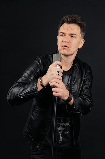 Low key portrait of man singing and holding microphone