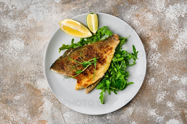 Top view od fried dorada fish with fresh arugula