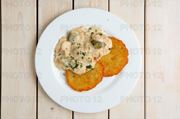 Potato pancakes with flour sauce and pickled cucumber and sausage