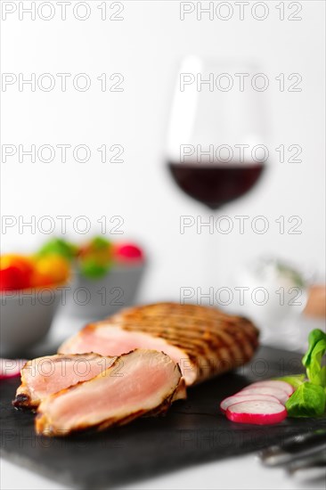 Grilled beef steak medium rare on stone board with fresh vegetables and glass of red wine. Photo with shallow depth of field