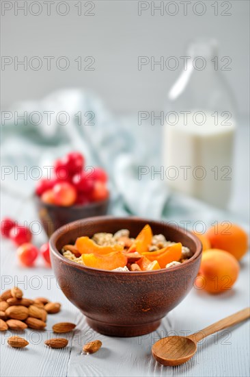 Muesli with apricots and almonds on white wooden table