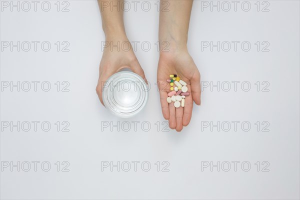 Flat lay hand holding pills glass water
