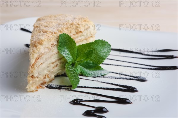 Piece of napoleon cake on plate with chocolate sauce. Puff pastry cake with custard