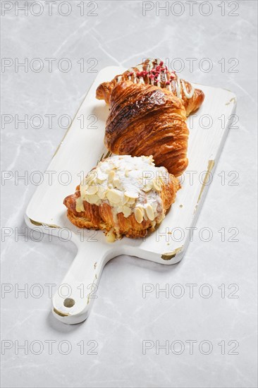 Various croissants on white serving board on marble background