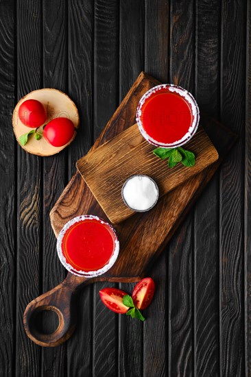 Overhead composition with salty tomato juice on dark wooten table