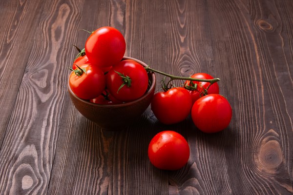 Branch of fresh tomatoes on wooden table