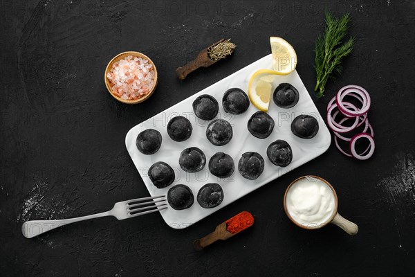 Black dumplings with beef with dough with cuttlefish ink on marble plate