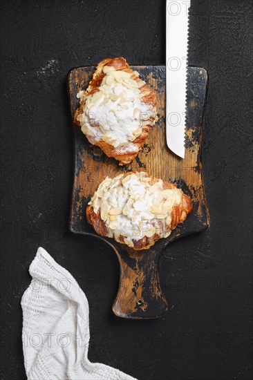 Top view of crispy croissant with caramel and peanut shavings on wooden serving board