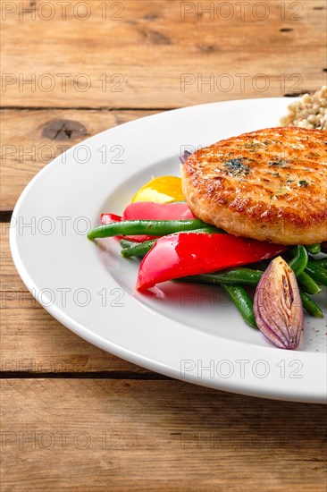 Close up view of salmon cutlet with roasted vegetables and green buckwheat