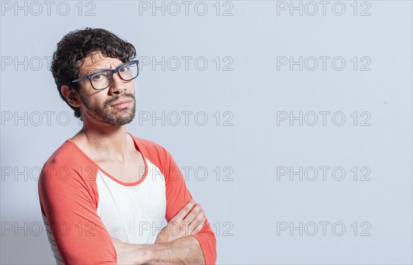 Young latin man in glasses with crossed arms looking in profile at the camera. Nicaraguan man with crossed arms looking at the camera isolated
