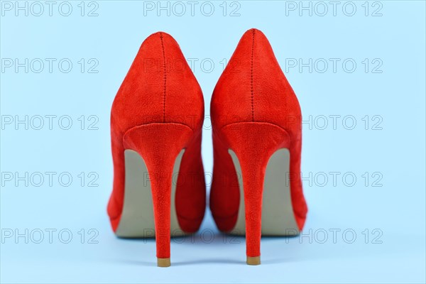 Back view of elegant red synthetic suede leather high heel woman shoes on blue background