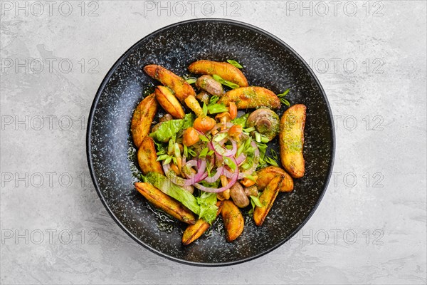 Top view of fried potato wedges with champignons dressed with red and white onion