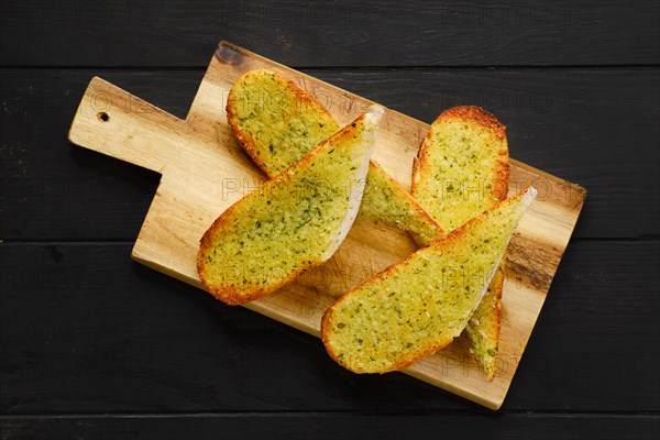 Crispy toasted garlic bread on wooden serving board