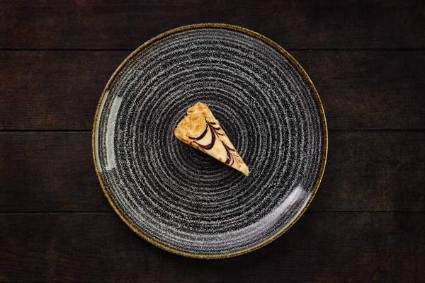 Top view of plate with piece of peanut cake on wooden background