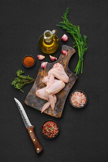 Overhead view of fresh uncooked chicken wings on wooden cutting board ready for cooking