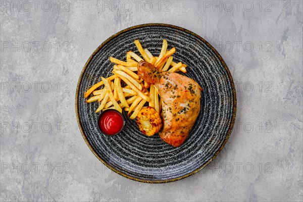 Top view of baked chicken thigh with french fries