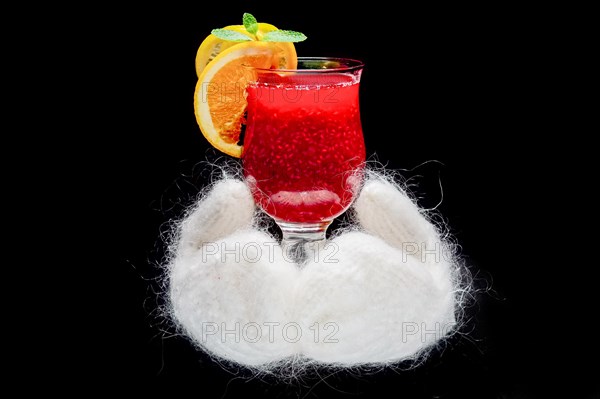 Hands in white warm mittens holding hot cup with fruit tea