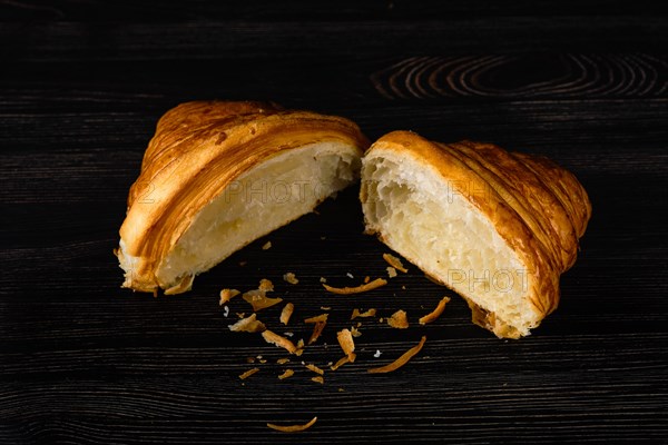 Fresh golden croissant on black table