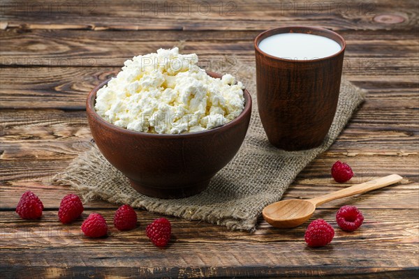 Cottage cheese and milk in clayware on wooden table