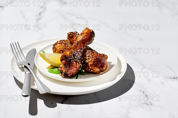 Portion of baked chicken legs with spicy sauce on a plate