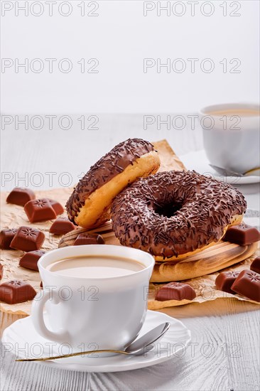 Chocolate donuts and coffee on bright wooden table