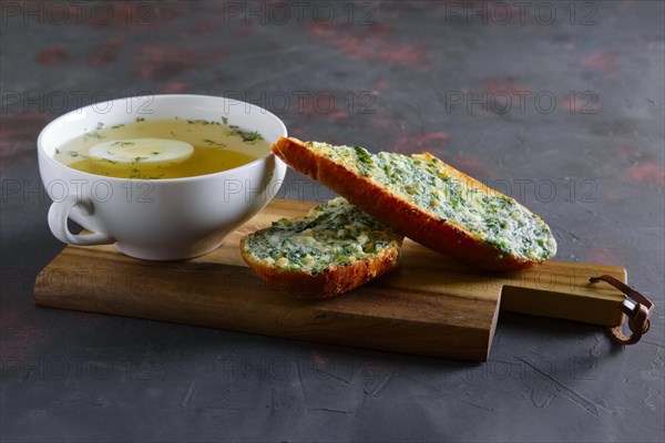 Clear chicken broth with egg served with toasts