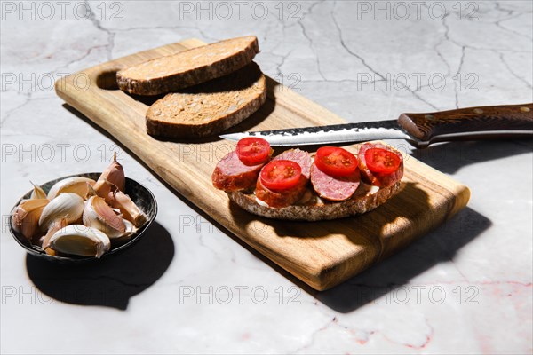 Sandwich with smoked pork sausage rings on wooden cutting board on kitchen table