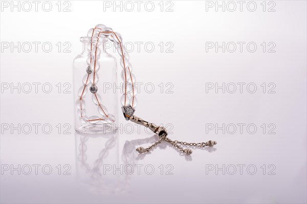 Prayer beads and bottle on a white background