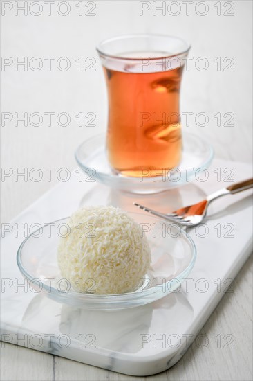 Closeup view of coconut biscuit dough cake and a cup of tea on a table