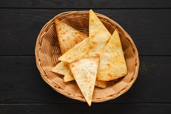 Top view of tortilla cut on triangular slices in wicker backet on a table