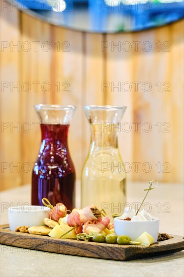 Two decanters with wine and plate with snack on background