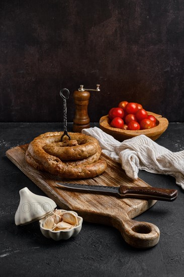 Horse meat sausage with garlic rolled on wooden cutting board