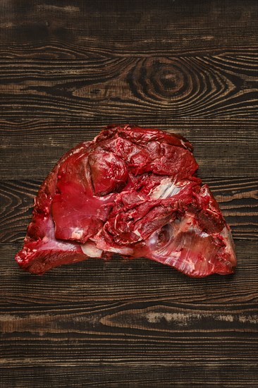 Overhead view of raw deer boneless ham over wooden background