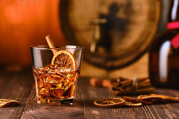 Glass of cocktail with whisky and orange liquor with barrel on background