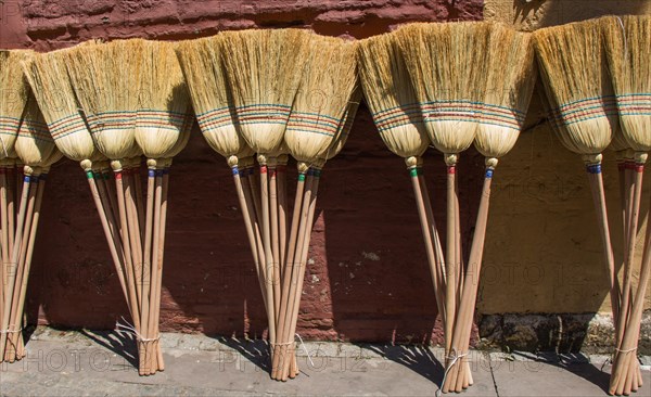 Set of yellow straw broom in a bazaar