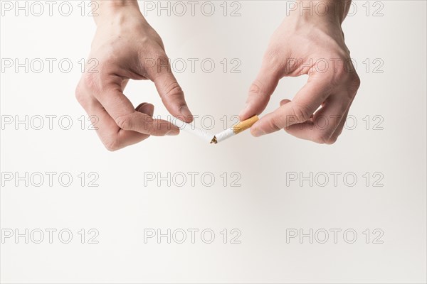 Person s hand breaking cigarette white background