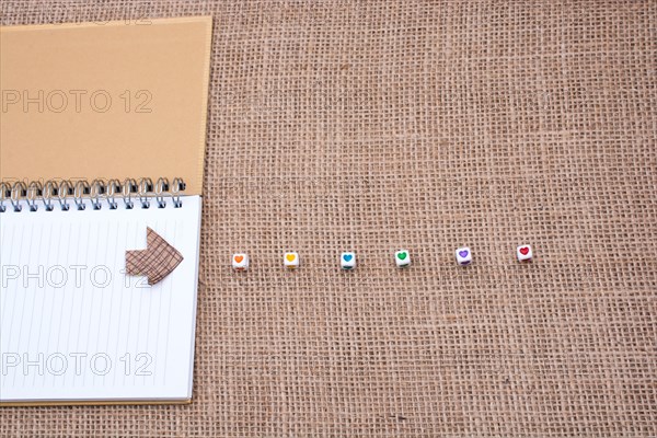 Love cubes and paper arrow on a notebook on canvas