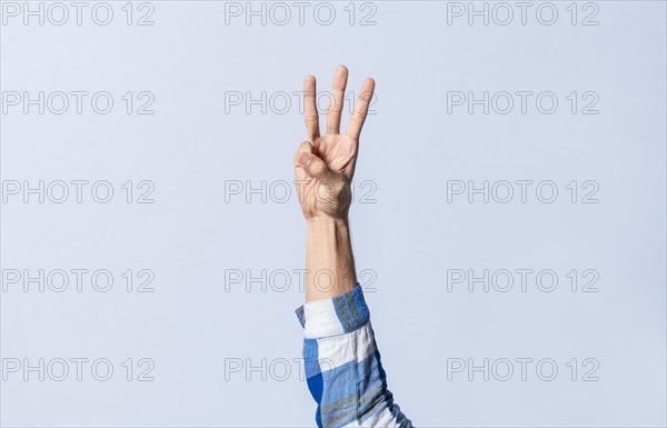 Hand gesturing the letter W in sign language on an isolated background. Man's hand gesturing the letter W of the alphabet isolated. Letter W of the alphabet in sign language