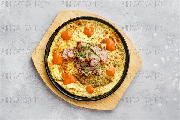 Top view of eggs with bacon and tomato baked in oven in cast-iron skillet