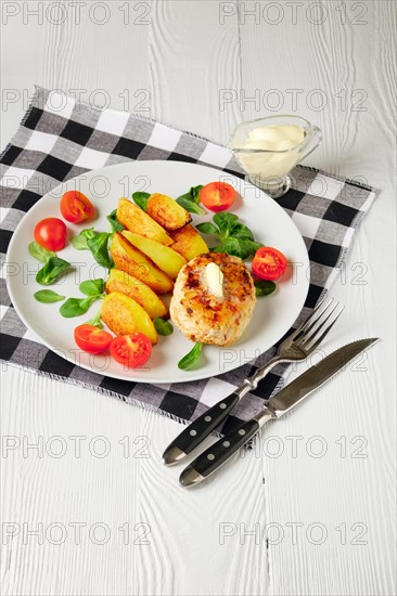 Fried chicken cutlet with potato slices served with tomato cherry and corn salad. Traditional belorussian food