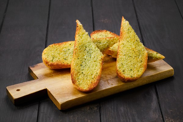 Crispy toasted garlic bread on wooden serving board