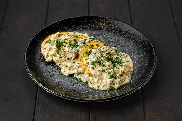 Potato patty with fried boletus and creamy sauce on a plate