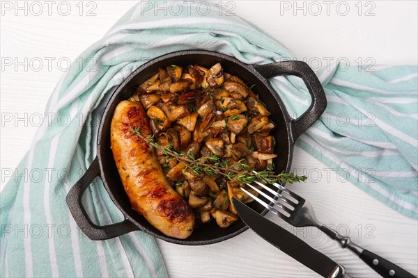 Cast-iron pan with fried sausage and mushrooms