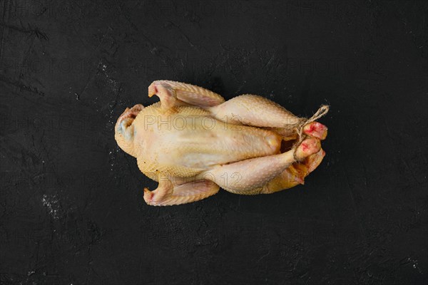 Raw whole chicken with spices on wooden cutting board